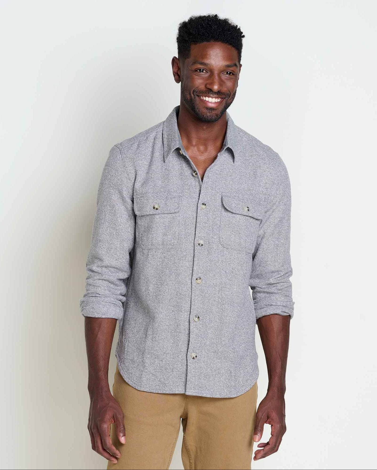 Man wearing a gray button-up shirt and beige pants against a white background